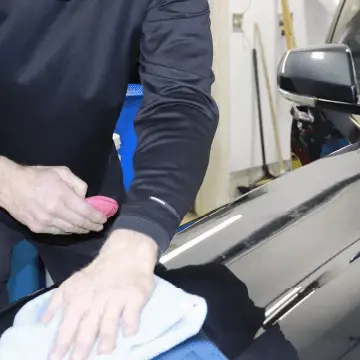 Hand waxing a car body with a microfiber cloth.