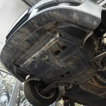Underside view of a car chassis raised on an auto repair lift.