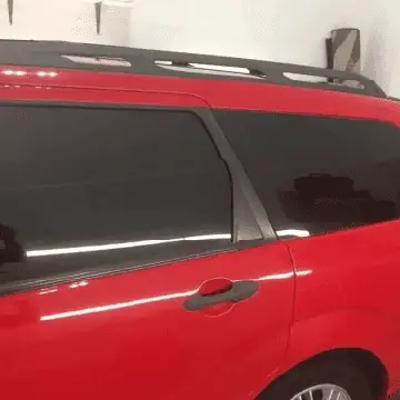Side view of a red vehicle showing heavily tinted rear windows.