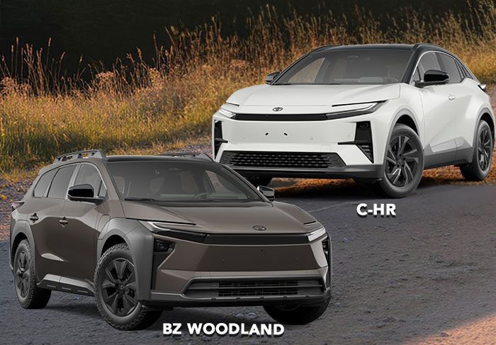 A smiling woman stands in a car dealership, looking at her smartphone while holding a takeaway coffee cup.