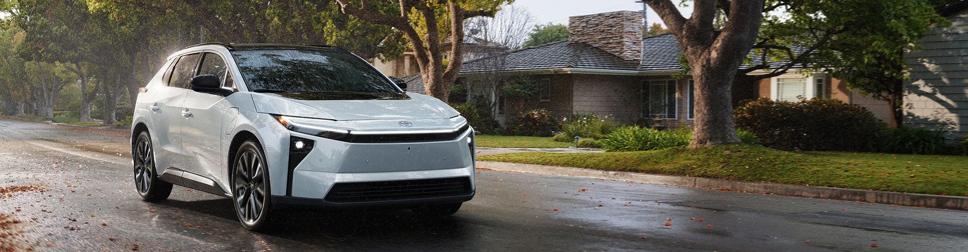 Side view of a white Toyota bZ electric SUV connected to a charger at an outdoor charging point.