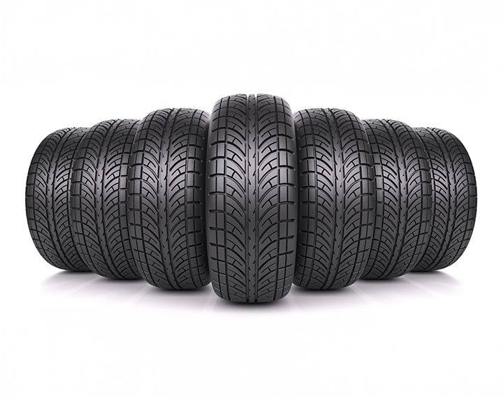 Six identical car tires arranged in a semi-circle, with one tire in the foreground and the others receding behind it. The tires are new with visible tread patterns.