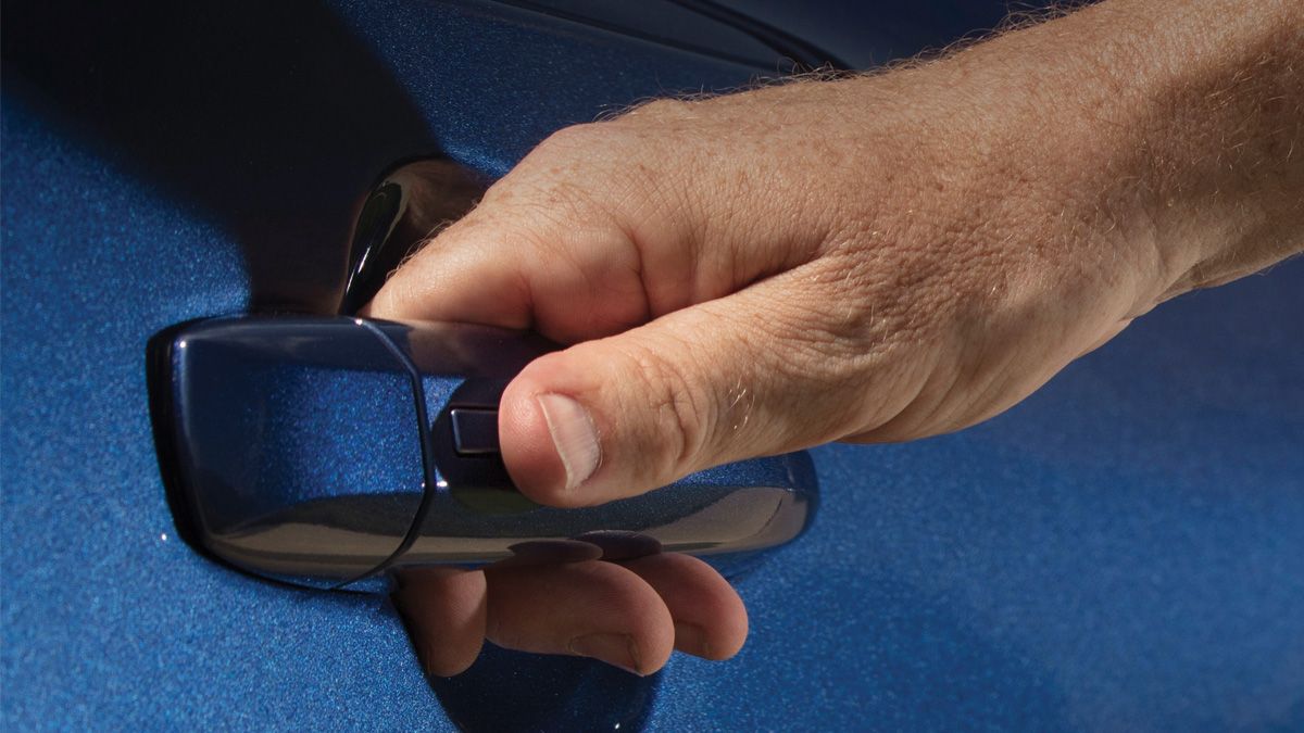 Smiling man wearing a red blazer, standing in a car dealership showroom.