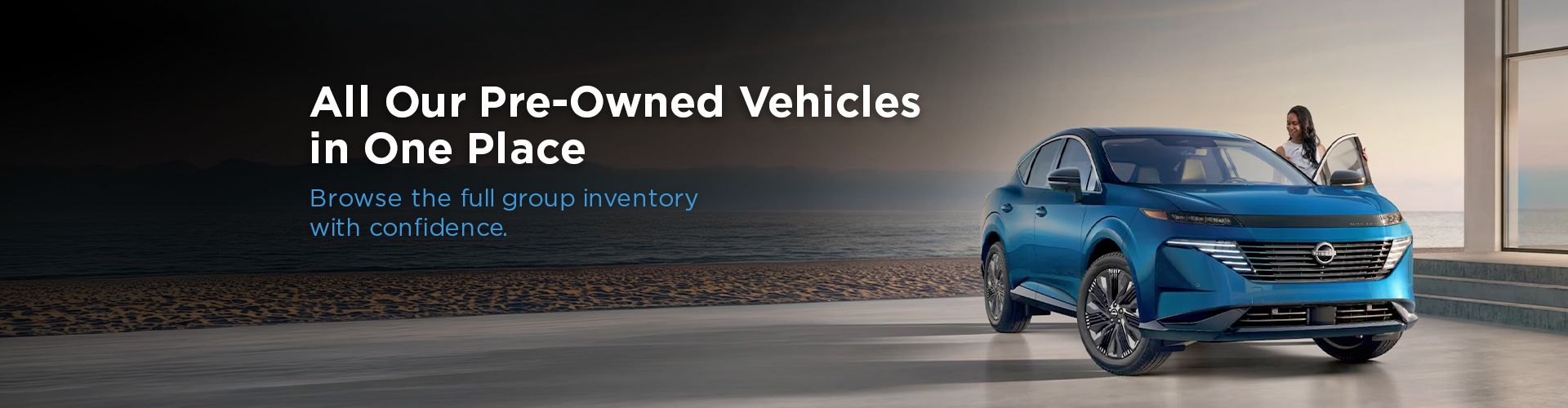 Blue Nissan SUV parked near the ocean with a woman opening the passenger door.