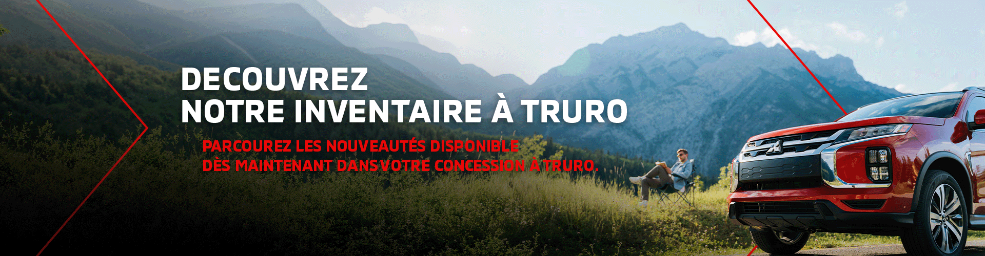 SUV Mitsubishi rouge stationné dans la nature devant des montagnes, avec un homme assit dans l'herbe en arrière-plan.