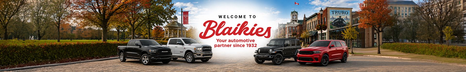Lineup of RAM, Jeep, and Dodge vehicles parked on a town square in front of the Blaikies welcome banner.