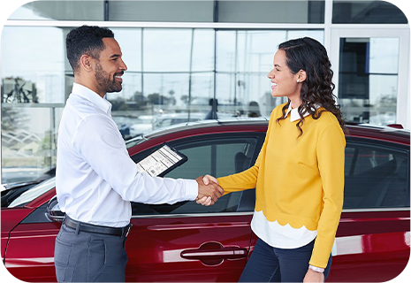 Conseiller d'un concessionnaire remettant des clés de voiture à une cliente souriante.