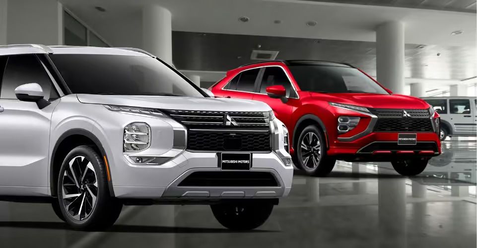 White and red Mitsubishi SUVs displayed inside a dealership showroom.