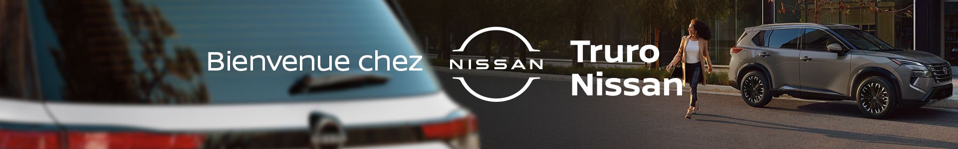 SUV Nissan gris stationné près d'un bâtiment moderne avec une femme marchant à côté et le logo Truro Nissan.