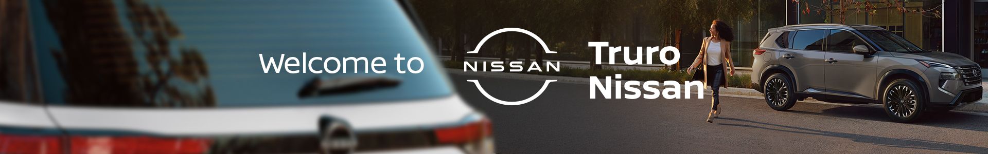 Grey Nissan SUV parked near a modern building with a woman walking nearby and the Truro Nissan logo.