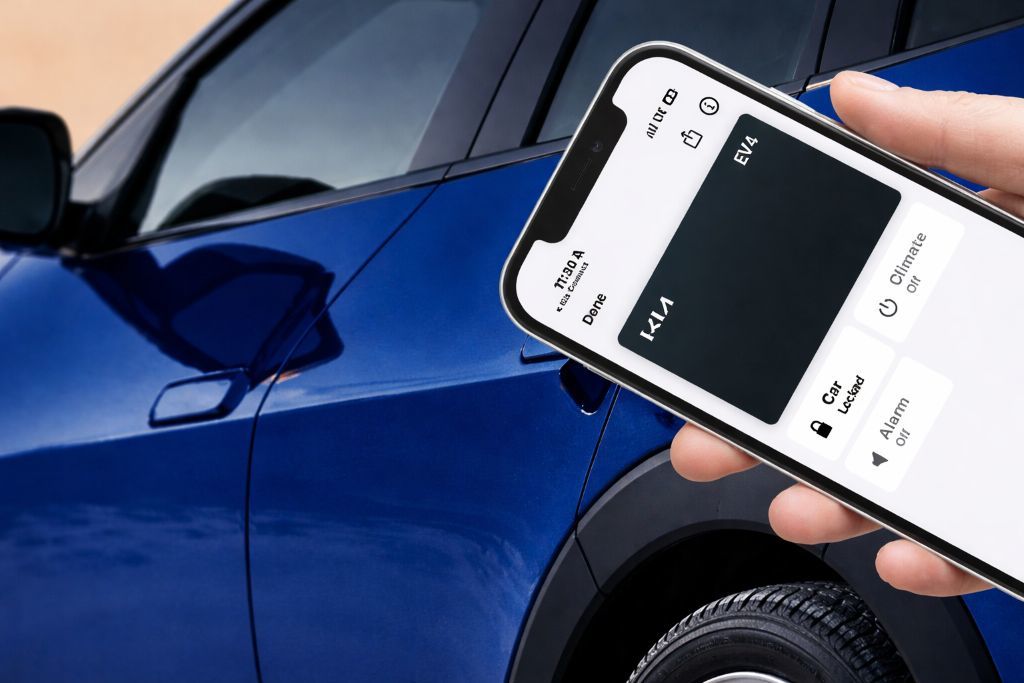 A smiling man sits in the driver's seat of a modern car, looking at his smartphone.