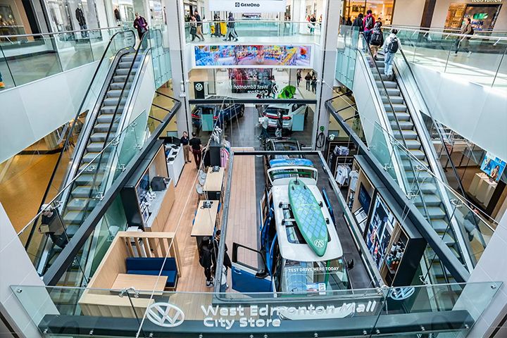 An overhead "bird's-eye" perspective from the upper level, showing the full layout including the lounge, cafe seating, and a blue ID. Buzz with a surfboard.