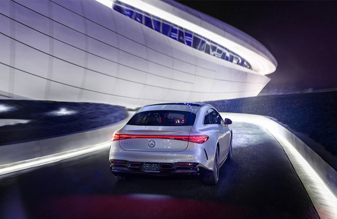 Rear view of a white Mercedes-Benz EQS driving through an illuminated tunnel