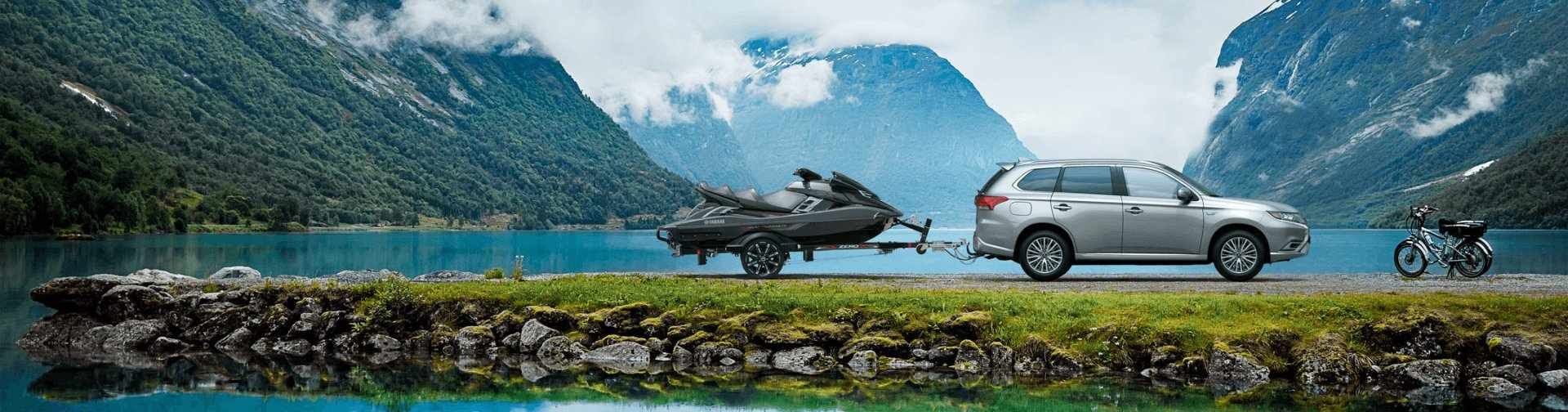 Mitsubishi Outlander remorquant un jet ski au bord d'un lac de montagne