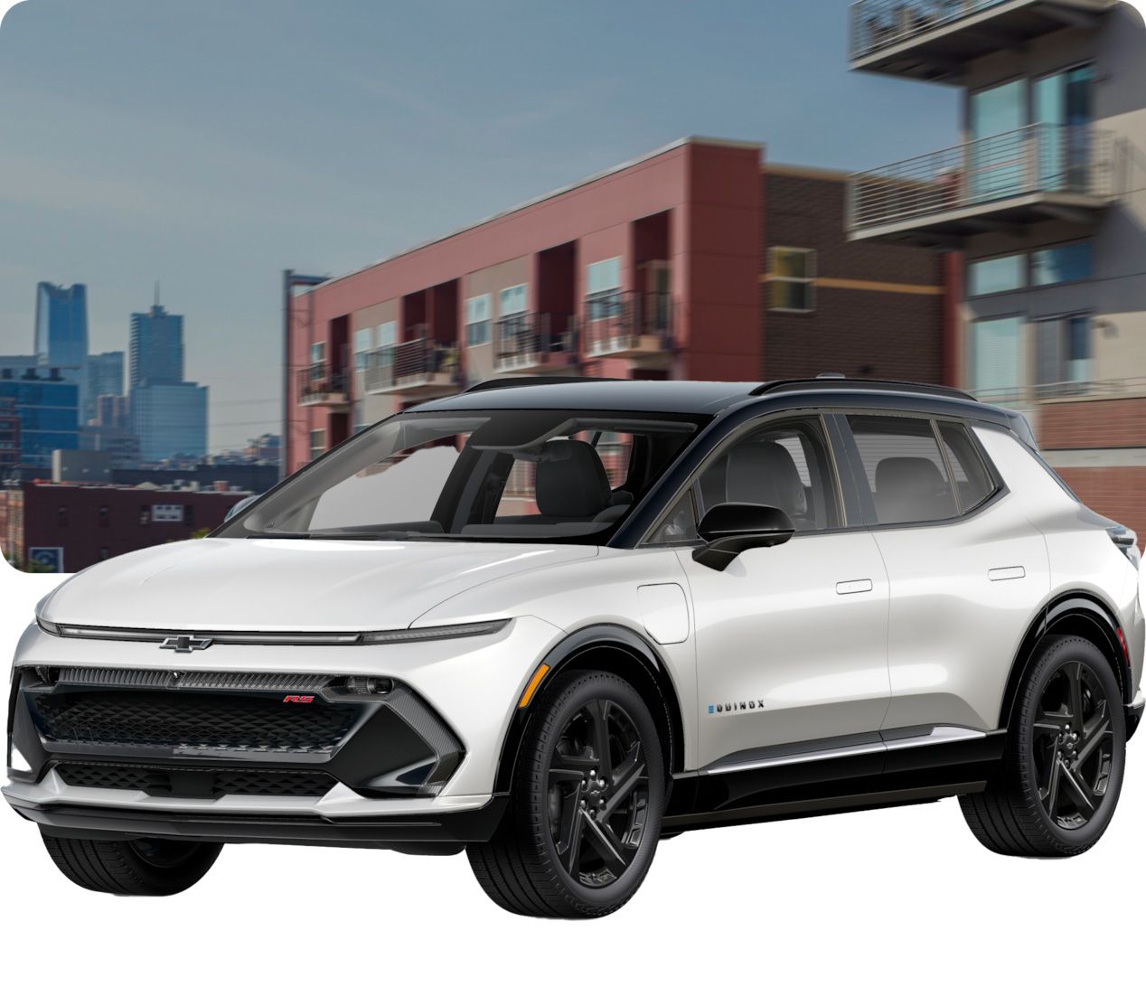 Une Chevrolet Equinox EV blanche avec un toit noir est garée dans une rue avec des bâtiments modernes en arrière-plan. La voiture a des roues noires et le mot « EQUINOX » écrit en bleu sur le côté.