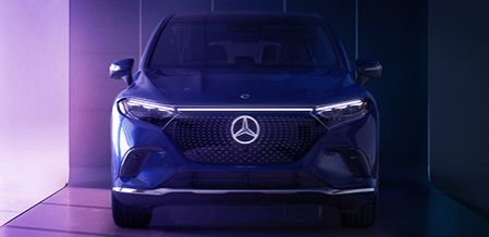 Front view of a blue Mercedes-Benz EQS SUV with headlights on