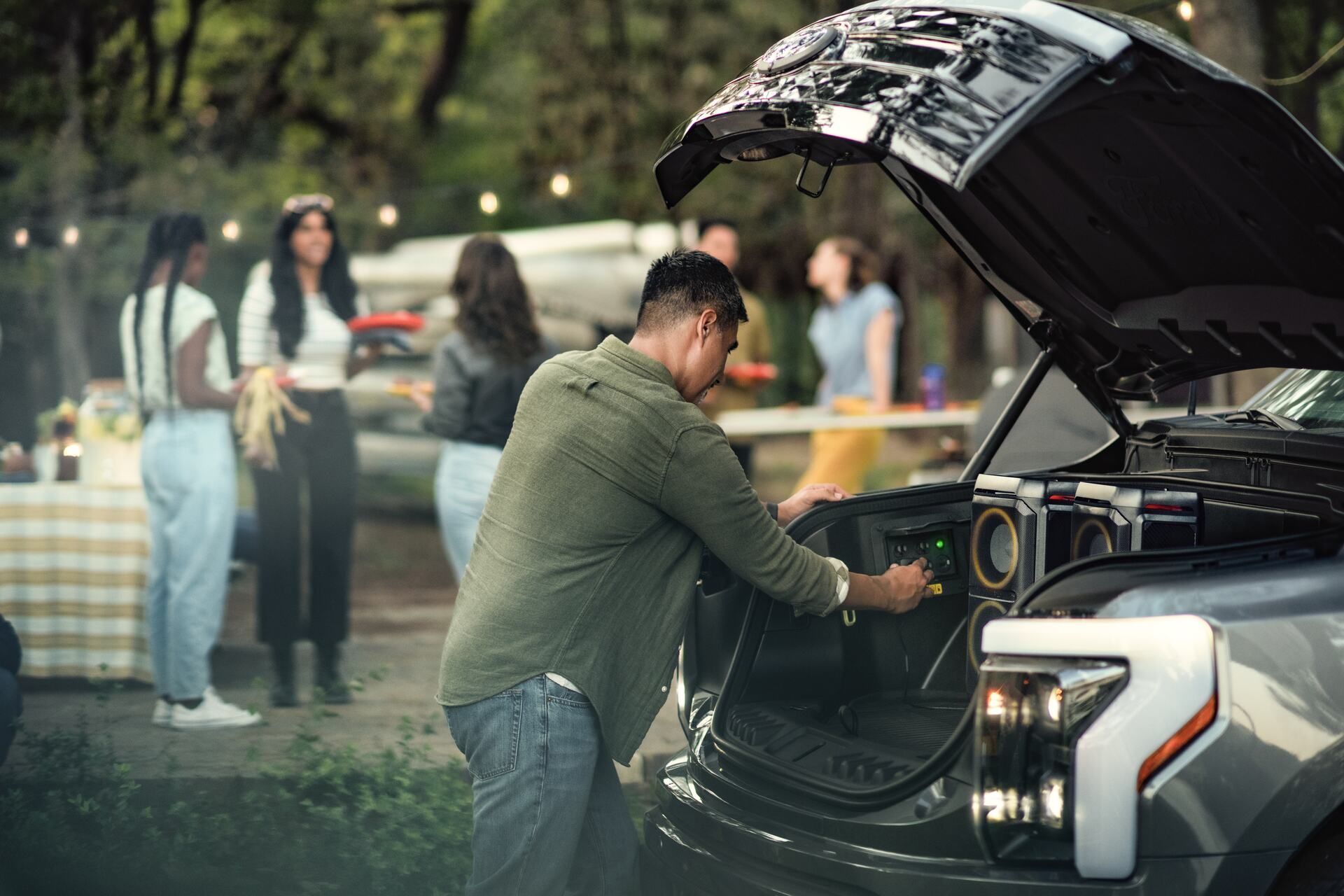 A man plugging in speakers into a 2024 Lightning® pickup with the front trunk open.