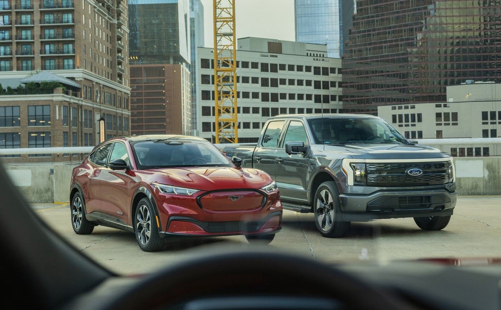 F150 Lightning and Mustang Mach-E parked on a rooftop with buildings in the background.