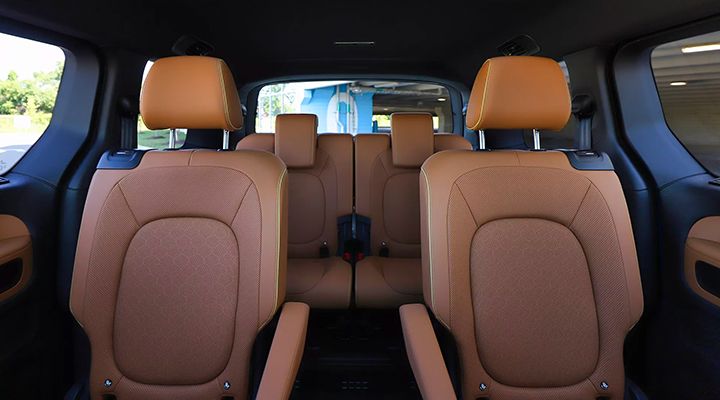 Interior view of a van showing the seating configuration in the second and third rows with brown upholstery.