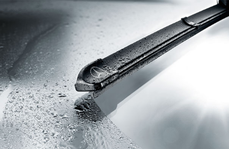 Gros plan sur un balai d'essuie-glace Mercedes-Benz mouillé par des gouttes d'eau.