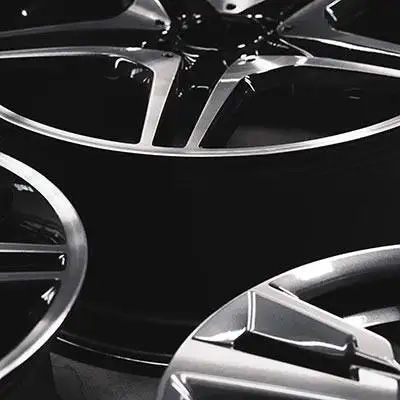 A stylized, black and white close-up of modern, multi-spoke alloy wheels, highlighting their sharp lines and metallic finish.