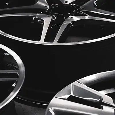 A stylized, black and white close-up of modern, multi-spoke alloy wheels, highlighting their sharp lines and metallic finish.