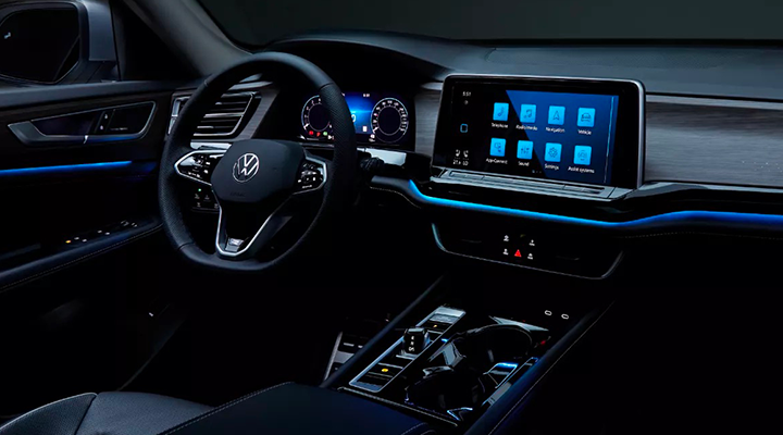 Interior view of a car at night, showing the dashboard and central screen illuminated with blue ambient lighting.
