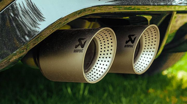 Close-up of the twin perforated Akrapovič exhaust tips of a car.