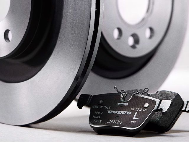 A close-up of a new brake disc and a Genuine Volvo brake pad resting in front of it.
