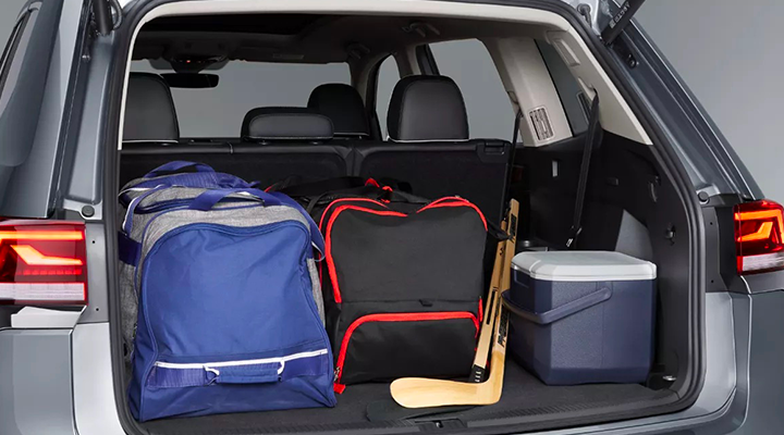 The trunk of an SUV is filled with hockey gear (duffel bags and a stick) and a cooler, illustrating the cargo space.
