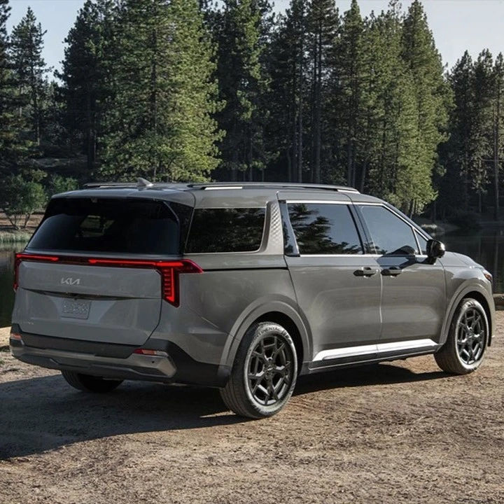 A silver Kia electric crossover parked on a mountain road with a forest in the background.