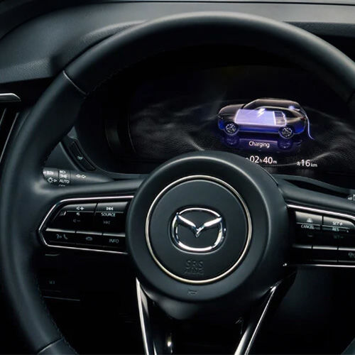 View of dash display behind the steering wheel inside the CX-90 PHEV shows battery level.  