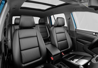 Vue de l'intérieur d'un véhicule, montrant les sièges en cuir noir de la première et de la deuxième rangée, avec un toit ouvrant.