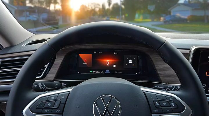 View from the driver's seat showing the steering wheel and the digital dashboard displaying the "Comfort" Drive Mode setting at sunset.