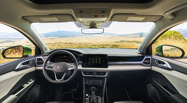 Interior view of the 2026 Volkswagen Taos, showing the dashboard, steering wheel, touchscreen display, and panoramic windshield.