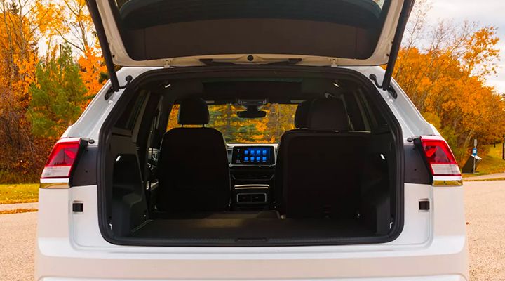 Rear view of the cargo area of a white SUV with the liftgate open, showing the rear seats folded down and the second-row seats upright.