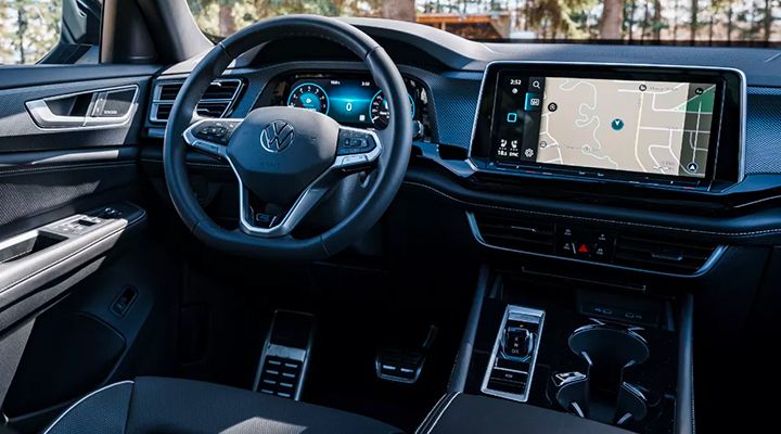 View of the Atlas or Atlas Cross Sport cockpit, showing the steering wheel, digital dash, large navigation screen, and aluminum sport pedals.