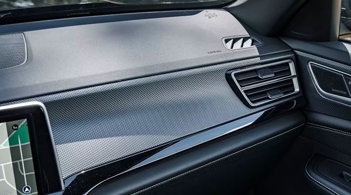 Close-up of the vehicle's dashboard interior, showing a textured trim with a carbon fiber-like pattern and air vents.