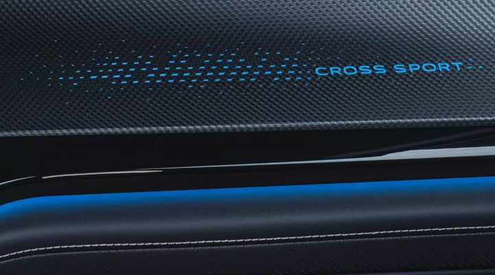 Close-up of the dashboard or door panel insert displaying the illuminated "CROSS SPORT" text with blue ambient lighting.
