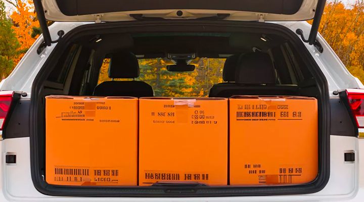 Rear view of the SUV's cargo area with the liftgate open, showing three large orange boxes filling the cargo space.