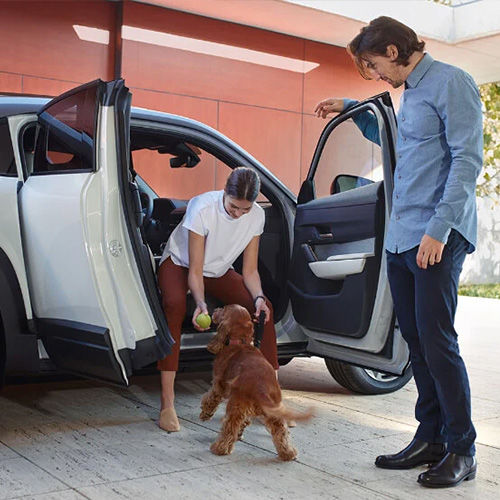 Couple plays with dog on the passenger side of an MX-30 with the freestyle doors open. 