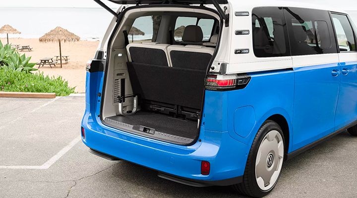 Vue arrière d'un Volkswagen ID. Buzz garé près d'une plage, avec son hayon grand ouvert révélant le coffre.