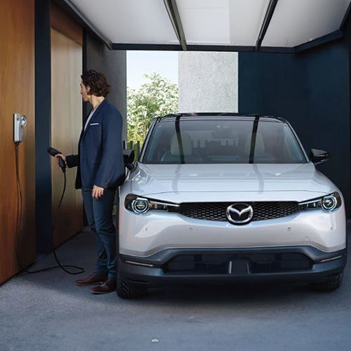 Driver unplugging a MX-30 EV in their garage.