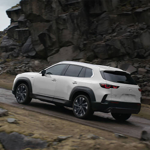 A white HEV drives uphill in rocky, mountainous terrain. 
