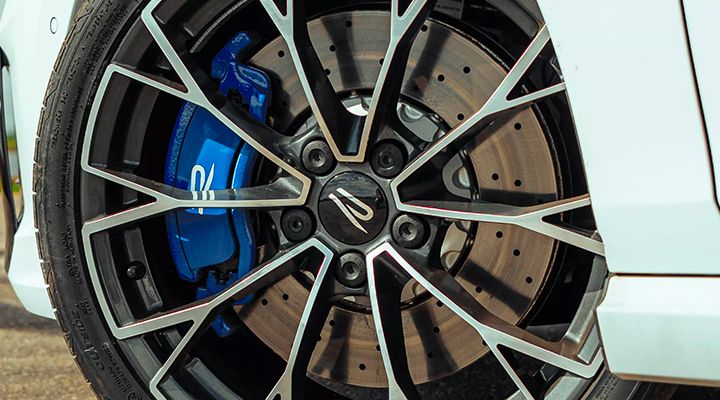 Gros plan sur une roue de voiture, mettant en évidence l'étrier de frein bleu et le disque perforé.