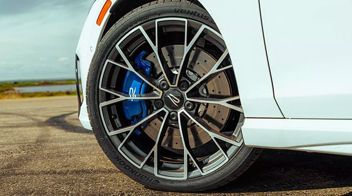 Close-up of a car's performance wheel, showing the multi-spoke rim and the blue brake caliper.