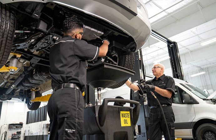 Two technicians servicing a Mercedes-Benz van