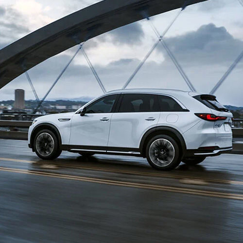CX-90 PHEV driving across road on suspension bridge.