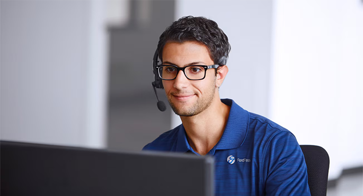 Un conseiller FordPass avec un casque audio devant un ordinateur, prêt à aider l'utilisateur.