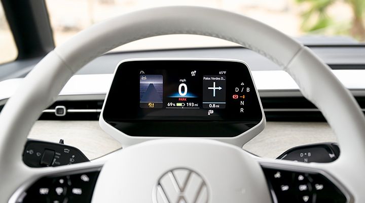 Close-up of the white steering wheel and the driver's screen, showing speed and navigation information.